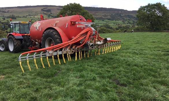 Slurry tanker applying slurry to a grass field with a dribble bar